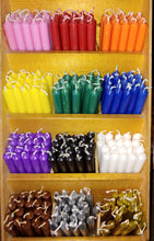 Load image into Gallery viewer, A shelf displaying an assortment of colorful magickal mini taper candles in various colors, including pink, purple, blue, green, white, and brown.
